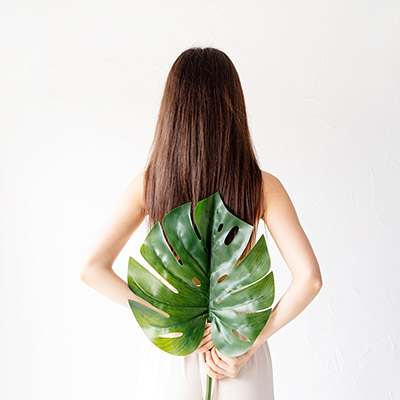 Woman holding a leaf behind her back